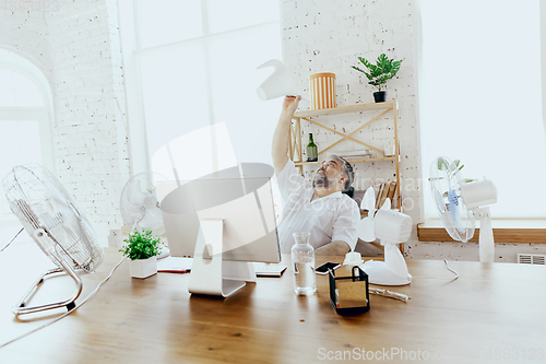 Image of Businessman, manager in office with computer and fan cooling off, feeling hot, flushed