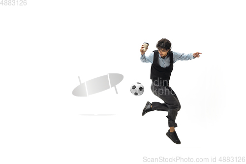 Image of Man in office clothes playing football or soccer with ball on white background. Unusual look for businessman in motion, action. Sport, healthy lifestyle.