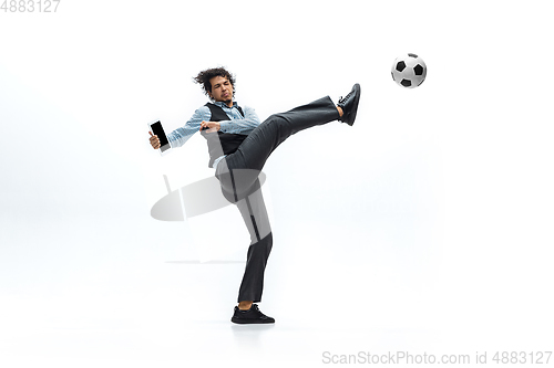 Image of Man in office clothes playing football or soccer with ball on white background. Unusual look for businessman in motion, action. Sport, healthy lifestyle.
