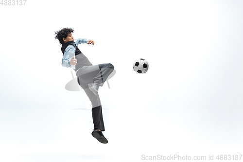 Image of Man in office clothes playing football or soccer with ball on white background. Unusual look for businessman in motion, action. Sport, healthy lifestyle.