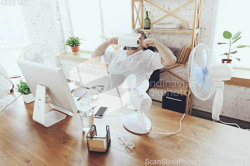 Image of Businessman, manager in office with computer and fan cooling off, feeling hot, flushed