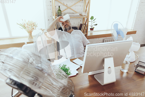 Image of Businessman, manager in office with computer and fan cooling off, feeling hot, flushed