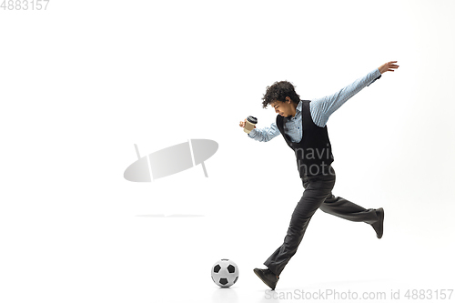 Image of Man in office clothes playing football or soccer with ball on white background. Unusual look for businessman in motion, action. Sport, healthy lifestyle.