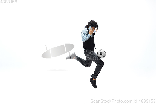 Image of Man in office clothes playing football or soccer with ball on white background. Unusual look for businessman in motion, action. Sport, healthy lifestyle.