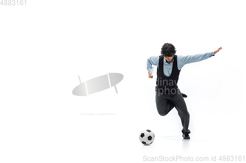 Image of Man in office clothes playing football or soccer with ball on white background. Unusual look for businessman in motion, action. Sport, healthy lifestyle.