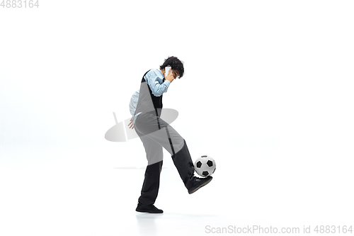Image of Man in office clothes playing football or soccer with ball on white background. Unusual look for businessman in motion, action. Sport, healthy lifestyle.