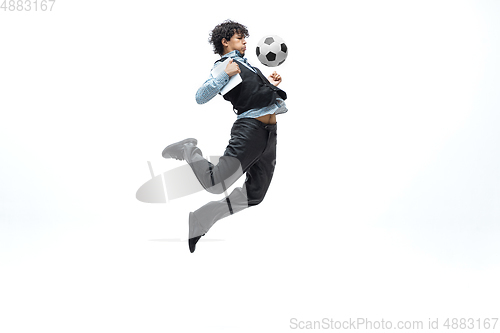 Image of Man in office clothes playing football or soccer with ball on white background. Unusual look for businessman in motion, action. Sport, healthy lifestyle.