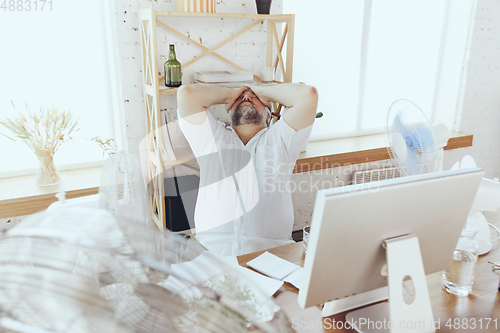 Image of Businessman, manager in office with computer and fan cooling off, feeling hot, flushed