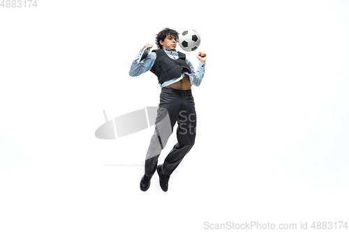 Image of Man in office clothes playing football or soccer with ball on white background. Unusual look for businessman in motion, action. Sport, healthy lifestyle.