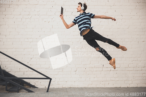 Image of Jumping young buinessman in front of buildings, on the run in jump high