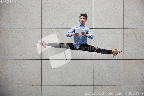 Image of Jumping young buinessman in front of buildings, on the run in jump high