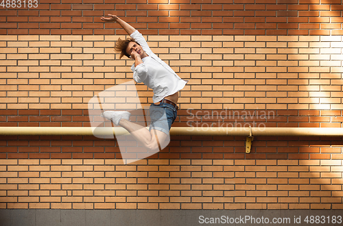 Image of Jumping young man in front of buildings, on the run in jump high