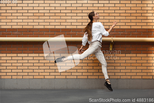 Image of Jumping young woman in front of buildings, on the run in jump high