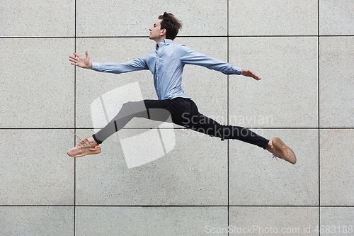 Image of Jumping young buinessman in front of buildings, on the run in jump high