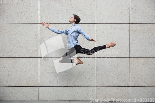 Image of Jumping young buinessman in front of buildings, on the run in jump high