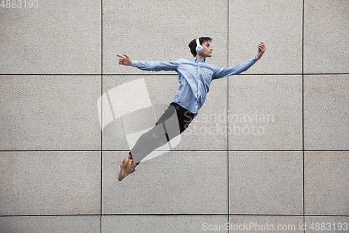 Image of Jumping young buinessman in front of buildings, on the run in jump high