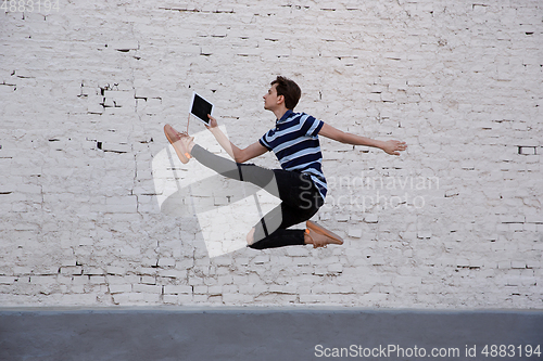 Image of Jumping young buinessman in front of buildings, on the run in jump high