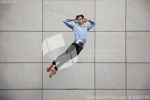 Image of Jumping young buinessman in front of buildings, on the run in jump high