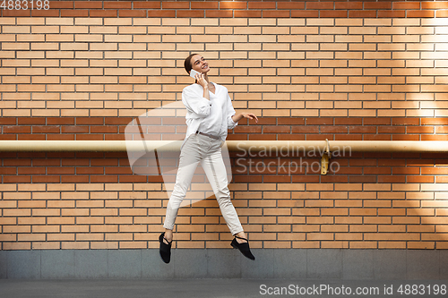 Image of Jumping young woman in front of buildings, on the run in jump high