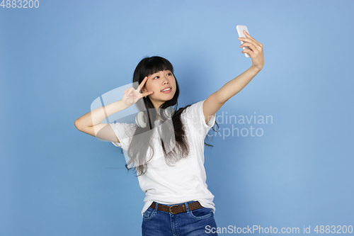 Image of Portrait of young asian woman isolated on blue studio background