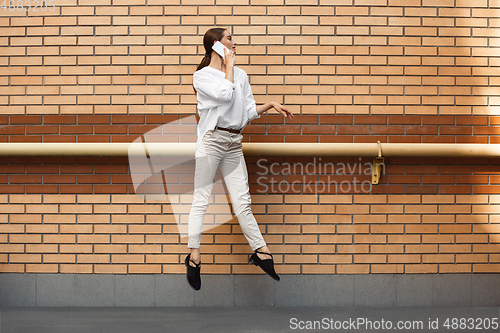 Image of Jumping young woman in front of buildings, on the run in jump high