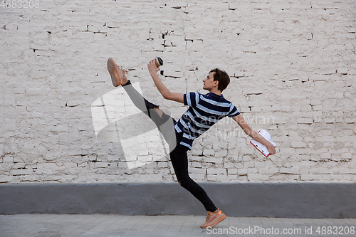 Image of Jumping young buinessman in front of buildings, on the run in jump high