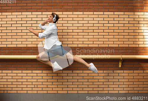 Image of Jumping young man in front of buildings, on the run in jump high