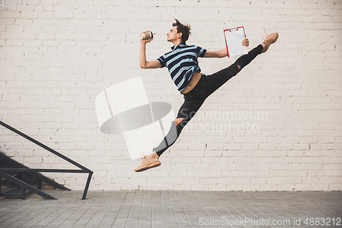 Image of Jumping young buinessman in front of buildings, on the run in jump high