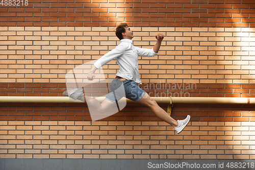 Image of Jumping young man in front of buildings, on the run in jump high