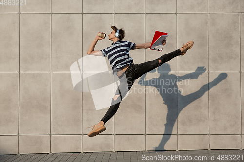 Image of Jumping young buinessman in front of buildings, on the run in jump high