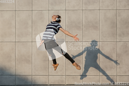 Image of Jumping young buinessman in front of buildings, on the run in jump high