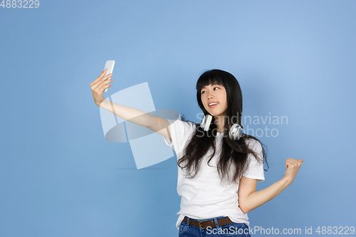 Image of Portrait of young asian woman isolated on blue studio background