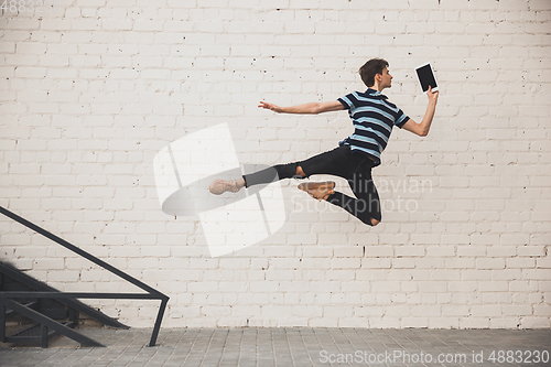 Image of Jumping young buinessman in front of buildings, on the run in jump high