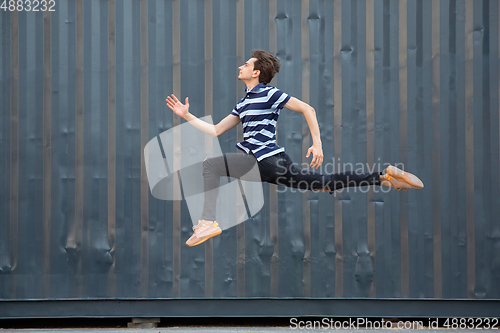 Image of Jumping young buinessman in front of buildings, on the run in jump high