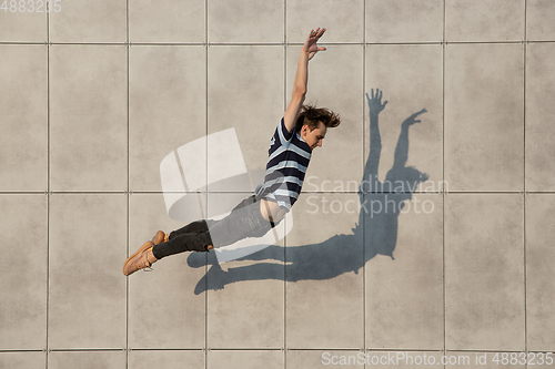 Image of Jumping young buinessman in front of buildings, on the run in jump high