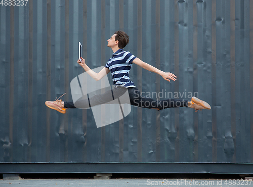 Image of Jumping young buinessman in front of buildings, on the run in jump high