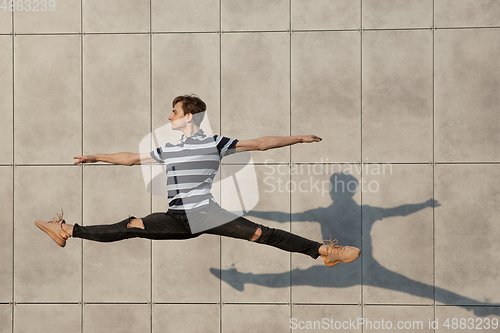 Image of Jumping young buinessman in front of buildings, on the run in jump high