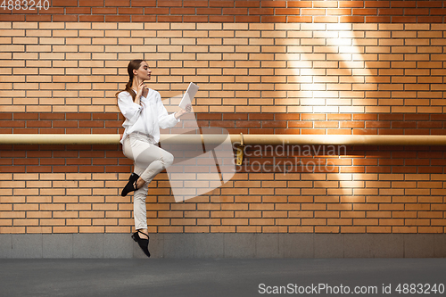 Image of Jumping young woman in front of buildings, on the run in jump high