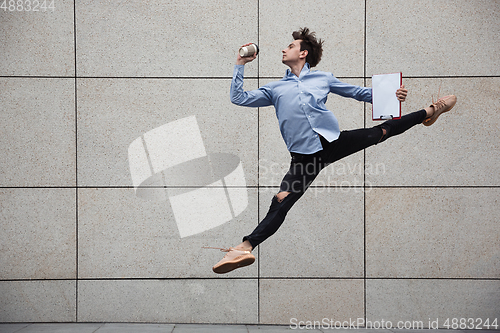 Image of Jumping young buinessman in front of buildings, on the run in jump high