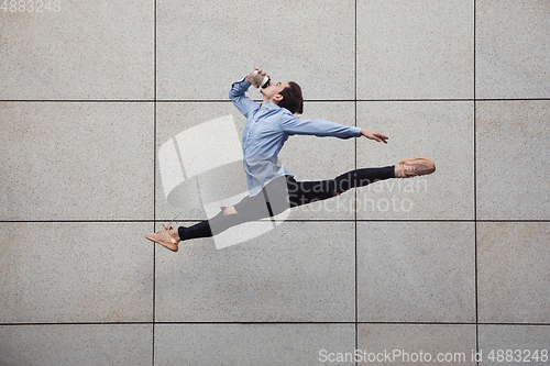 Image of Jumping young buinessman in front of buildings, on the run in jump high