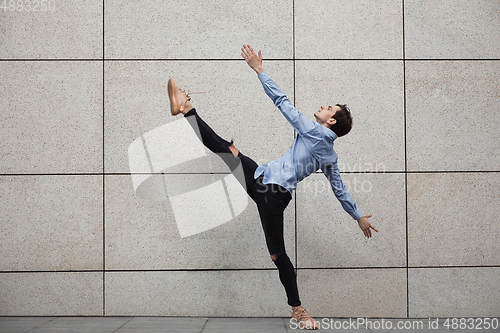 Image of Jumping young buinessman in front of buildings, on the run in jump high