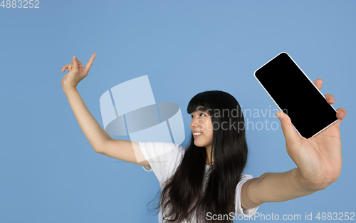 Image of Portrait of young asian woman isolated on blue studio background