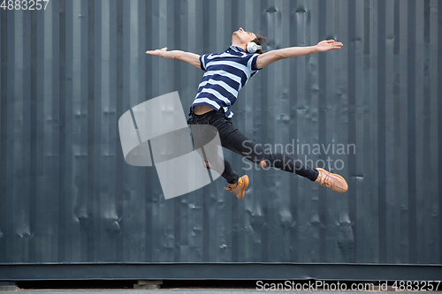 Image of Jumping young buinessman in front of buildings, on the run in jump high