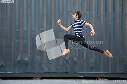 Image of Jumping young buinessman in front of buildings, on the run in jump high