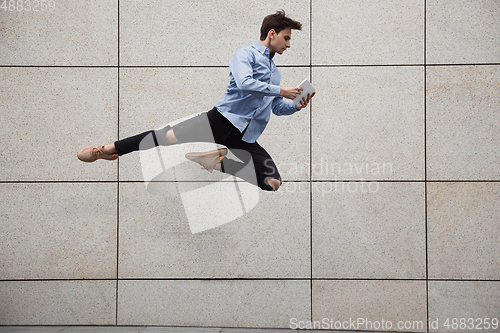 Image of Jumping young buinessman in front of buildings, on the run in jump high