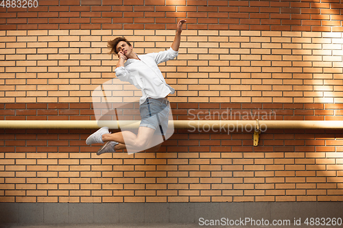 Image of Jumping young man in front of buildings, on the run in jump high