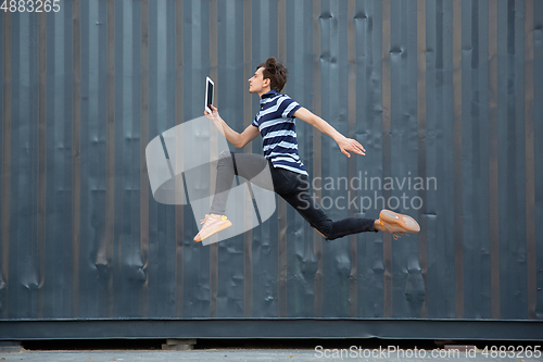 Image of Jumping young buinessman in front of buildings, on the run in jump high