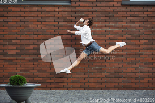 Image of Jumping young man in front of buildings, on the run in jump high