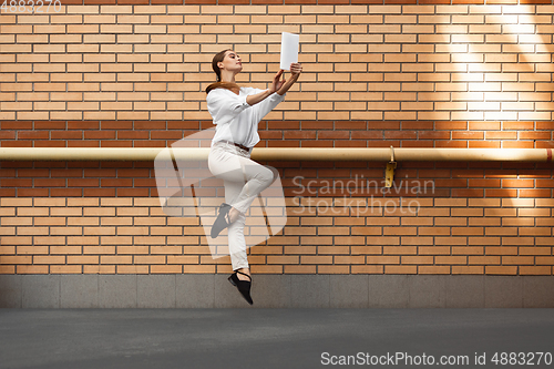 Image of Jumping young woman in front of buildings, on the run in jump high