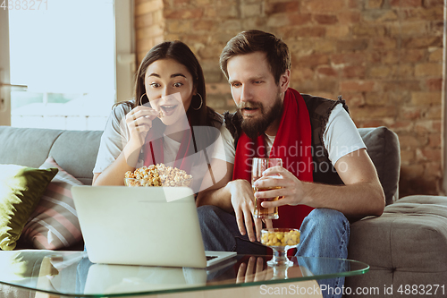 Image of Excited football fans watching sport match at home, remote support of favourite team during coronavirus pandemic outbreak
